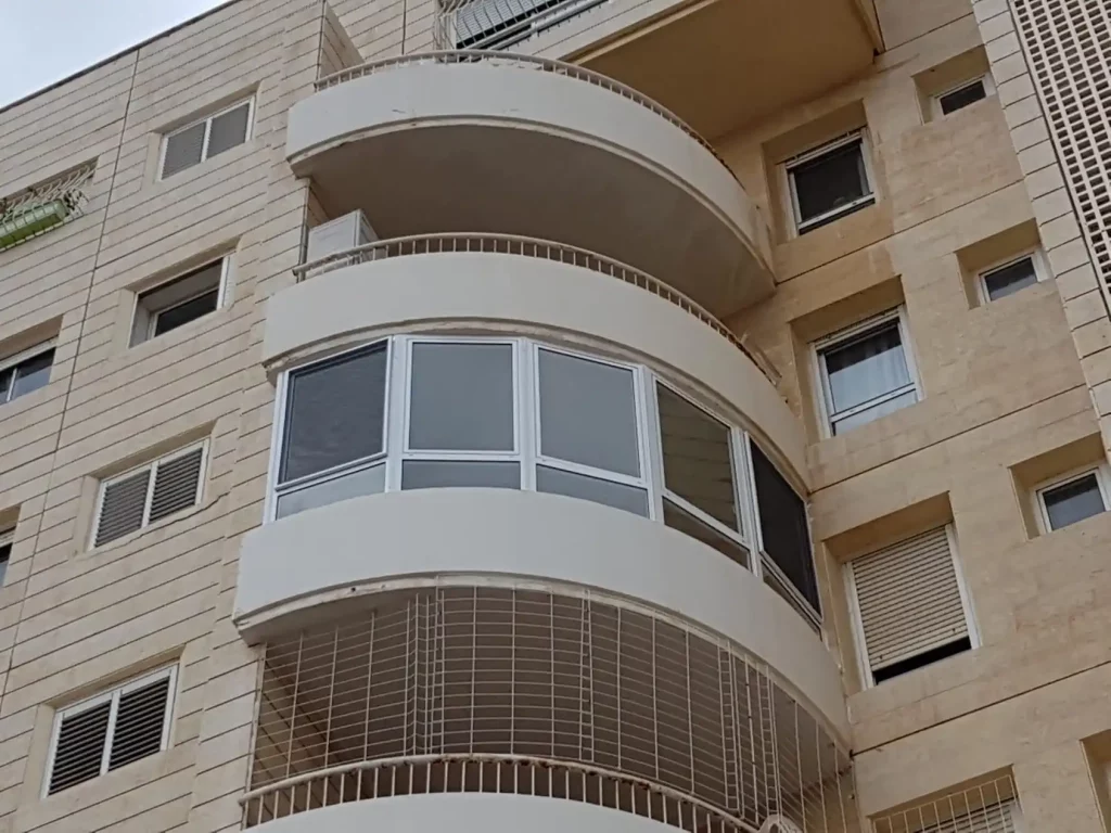 סגירת מרפסת מעוגלת מאלומיניום וזכוכית בחזית בניין מגורים