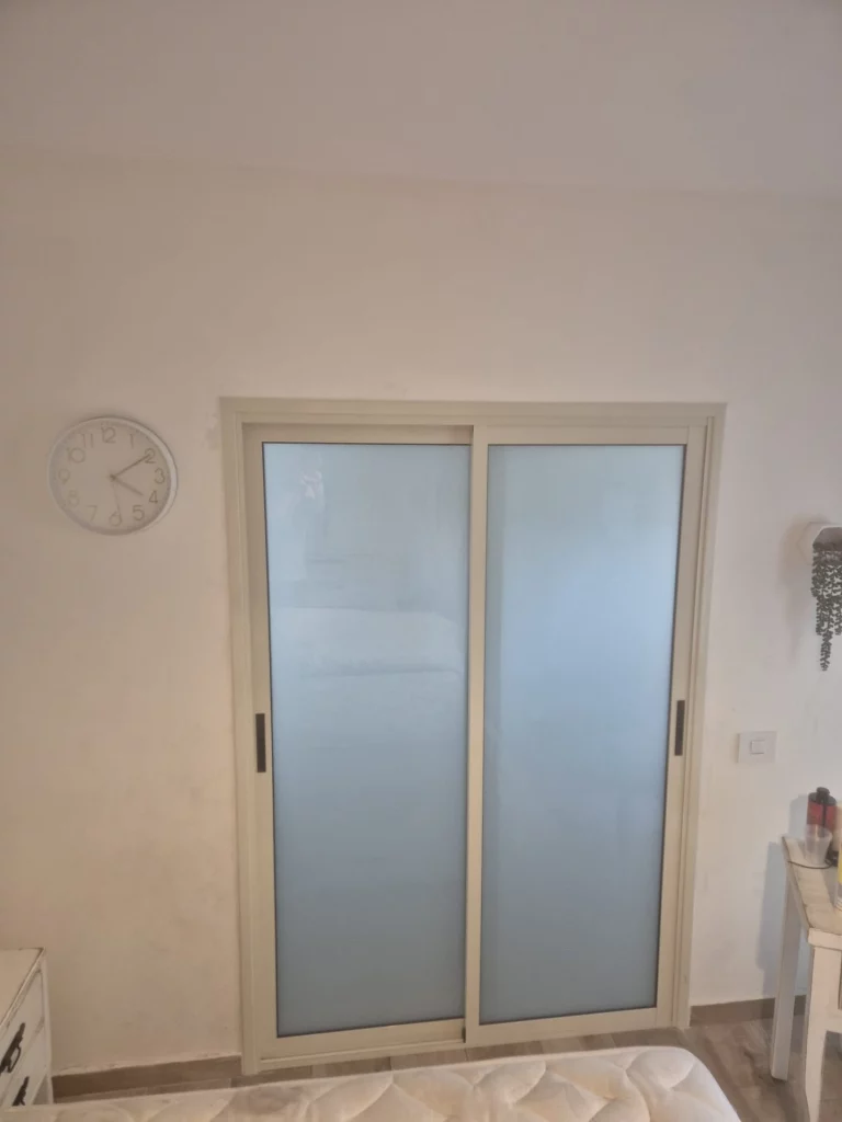 דלת הזזה מאלומיניום עם זכוכית חלבית בחדר שינה